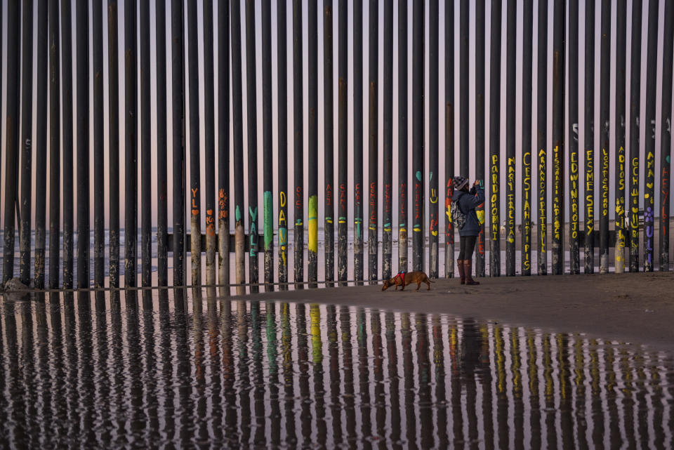 FILE - In this Jan. 3, 2019, file photo, a woman takes a photo by the border fence between San Diego, Calif., and Tijuana, as seen from Mexico. The top House Republican says a bipartisan border security compromise that Congress hopes to produce doesn't have to include the word "wall." (AP Photo/Daniel Ochoa de Olza, File)