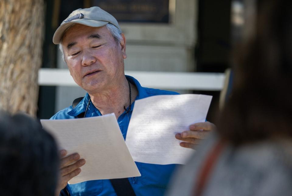 Darrell Kunitomi reads aloud while holding a letter outdoors