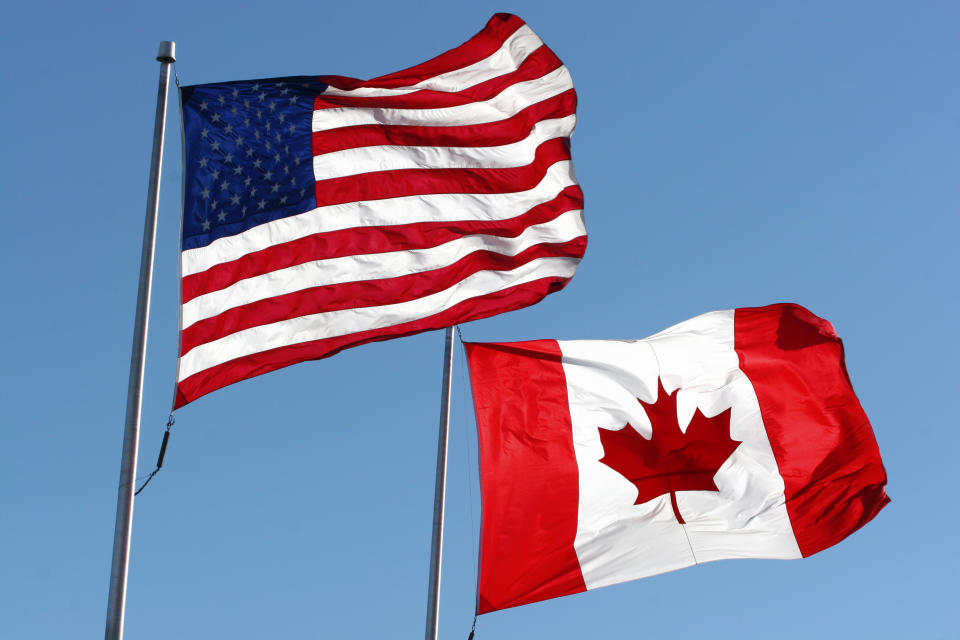 An American & Canadian flag waving in the wind.