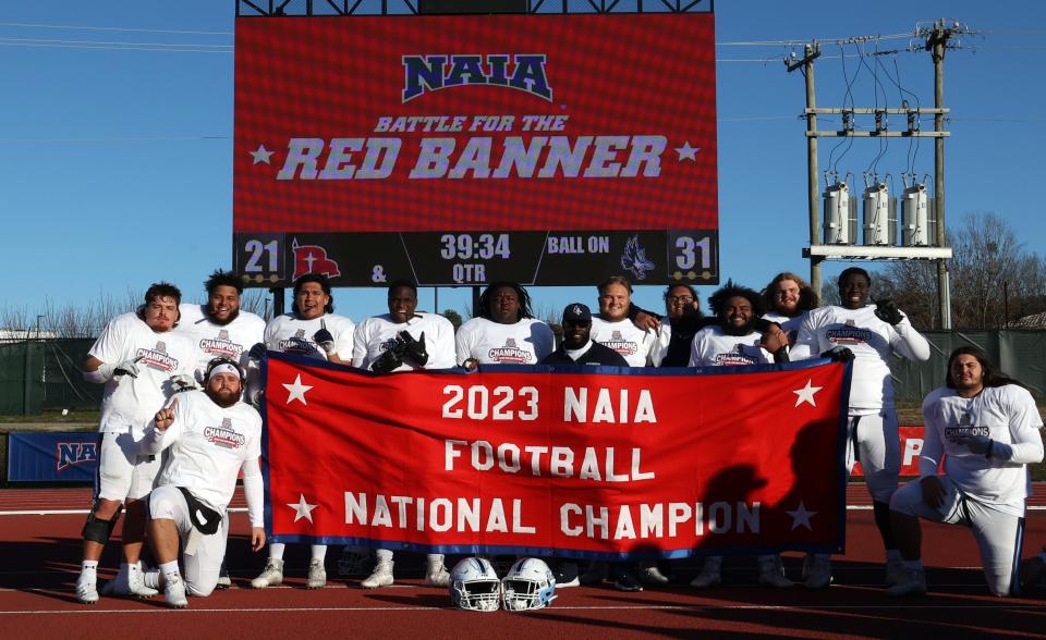 Keiser University players pose with the national championship banner after defeating Northwestern (Iowa) Monday in Durham, N.C.