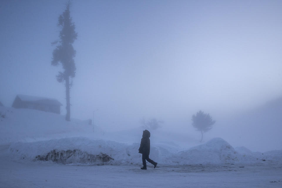 An Indian tourist enjoys a morning walk on a snow covered road on a cold and foggy morning in Gulmarg, northwest of Srinagar, Indian controlled Kashmir, Monday, Jan. 11, 2021. Snow this winter has brought along with it thousands of locals and tourists to Indian-controlled Kashmir's high plateau, pastoral Gulmarg, which translates as “meadow of flowers." (AP Photo/ Dar Yasin)