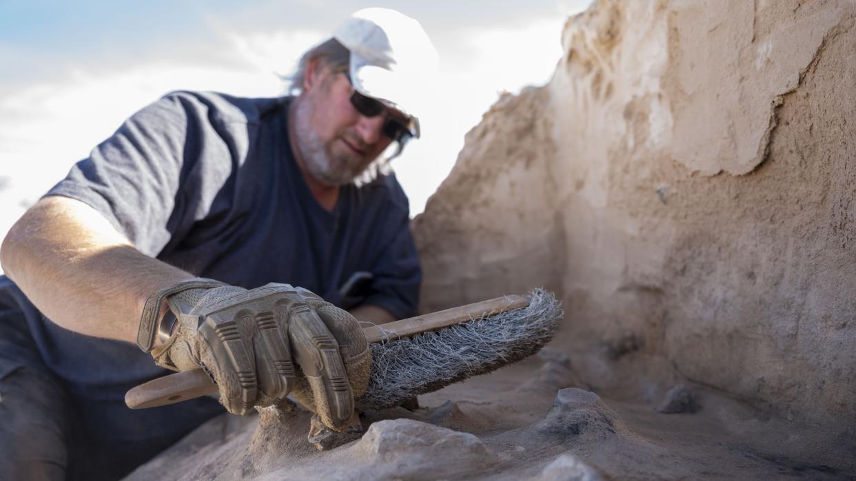  A man brushes sand off the remnants of a prehistoric campsite in New Mexico. 