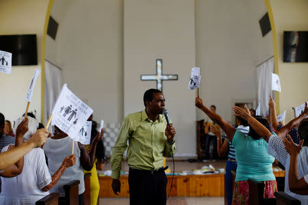 Assistant pastor Henry Nurse preaches as worshippers wave paper flags that read in Spanish "I am in favour of the original design. The family as God created it. Wedding between man and woman", during a service at a Methodist Church in Havana, Cuba, October 4, 2018. REUTERS/Alexandre Meneghini