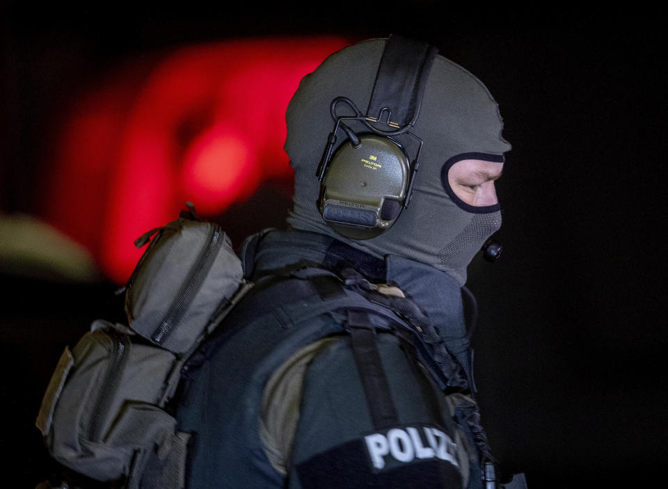 A special forces officer guards the road in front of a house that is searched through by police in Hanau, Germany Thursday, Feb. 20, 2020. Eight people were killed in shootings in and outside two hookah lounges in a southwestern German city late Wednesday, and authorities were searching for the perpetrators. (AP Photo/Michael Probst)