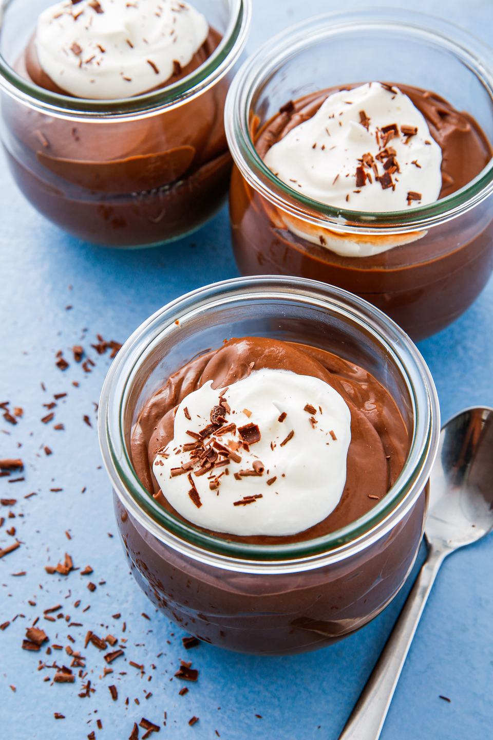 three cups of chocolate pudding on a blue background