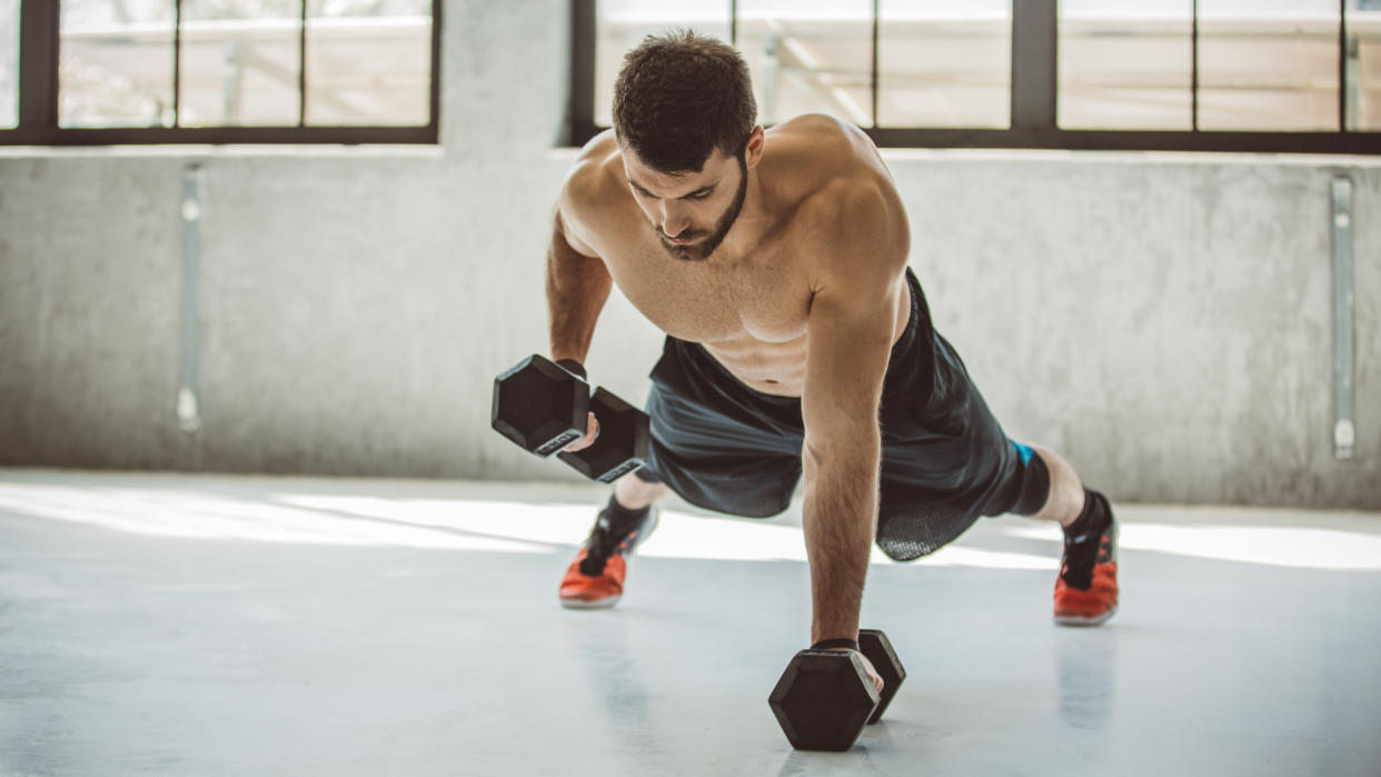  Man performing dumbbell renegade rows. 