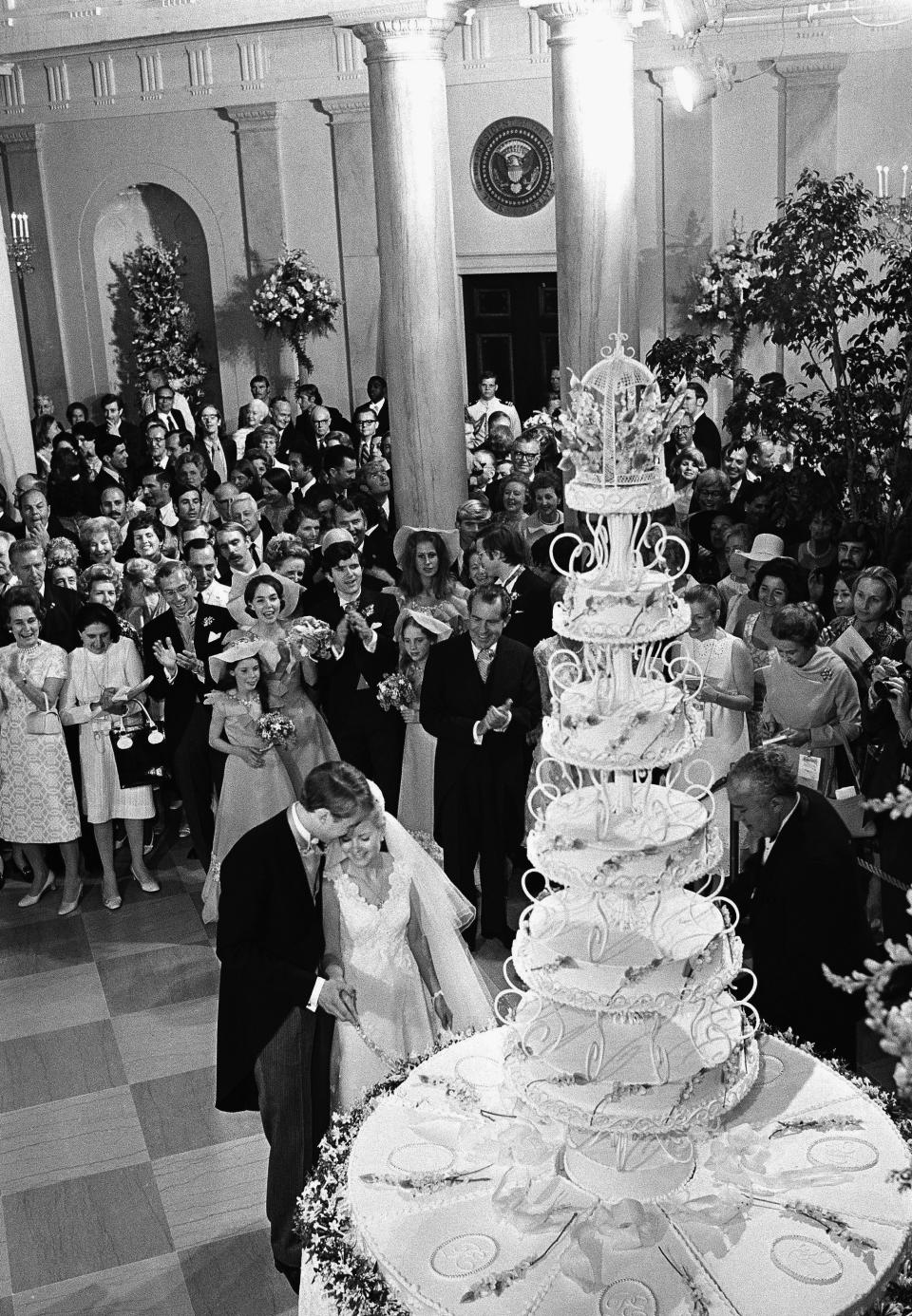 FILE - President Richard Nixon applauds as his daughter Tricia and her husband Edward Finch Cox, cut a giant wedding cake at the White House, June 12, 1971. (AP Photo, File)