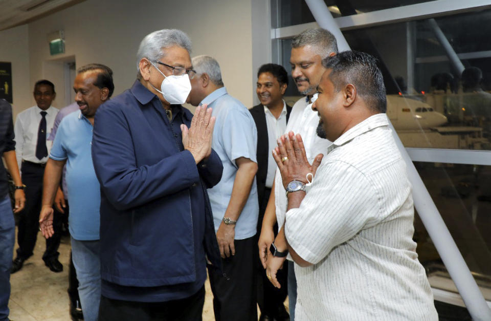 In this handout picture provided by the Ministry of Urban Development and Housing of Government of Sri Lanka, Sri Lanka's former President Gotabaya Rajapaksa, wearing mask, is greeted upon his arrival at Bandaranaike International airport in Colombo, Sri Lanka, Saturday, Sept. 3, 2022. Gotabaya Rajapaksa, who fled the country in July after tens of thousands of protesters stormed his home and office in a display of anger over the country's economic crisis, has returned to the country after seven weeks. (Ministry of Urban Development and Housing of Government of Sri Lanka via AP Photo)