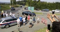 People attend the arrival of the car convoy of Russia's President Vladimir Putin on its way for the wedding of Austria's Foreign Minister Karin Kneissl and Wolfgang Meilinger in Sulztal an der Weinstrasse, Austria, Saturday, Aug. 18, 2018. (AP Photo/Ronald Zak)