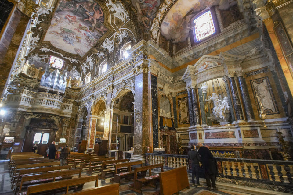 Visitors admire the marble sculptural group "Ecstasy of Saint Teresa" made between 1647 and 1652, by Baroque architect and sculptor Gian Lorenzo Bernini, in the Cornaro Chapel of Rome's Saint Mary of Victory church, Tuesday, Dec. 15, 2020. Like elsewhere in Europe, museums and art galleries in Italy were closed this fall to contain the spread of COVID-19, meaning art lovers must rely on virtual tours to catch a glimpse of the treasures held by famous institutions such as the Uffizi in Florence and the Vatican Museums in Rome. However, some exquisite gems of Italy's cultural heritage remain on display in real life inside the country's churches, some of which have collections of renaissance art and iconography that would be the envy of any museum. (AP Photo/Andrew Medichini)