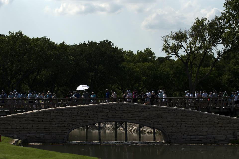 A patron attempts to shade themselves by holding an umbrella while they walk to the 18th hole during the third round of the AT&T Byron Nelson golf tournament in McKinney, Texas, on Saturday, May 14, 2022. (AP Photo/Emil Lippe)