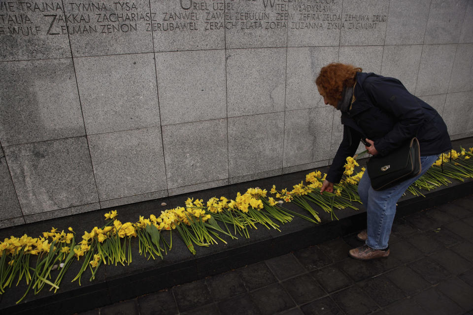 A woman places a yellow tulip at 'The Umschlagplatz' monument during personal unofficial observances marking the 80th anniversary of the Warsaw Ghetto Uprising in Warsaw, Poland, Wednesday, April 19, 2023. (AP Photo/Michal Dyjuk)