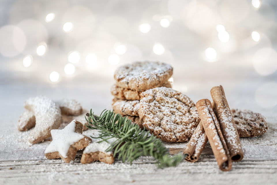 Vegane Weihnachten. Mit Puderzucker bestäubte Haferkekse, Zimtstangen, Zimtsterne und Vanillekipferl auf einem Holztisch mit Tannenzweig