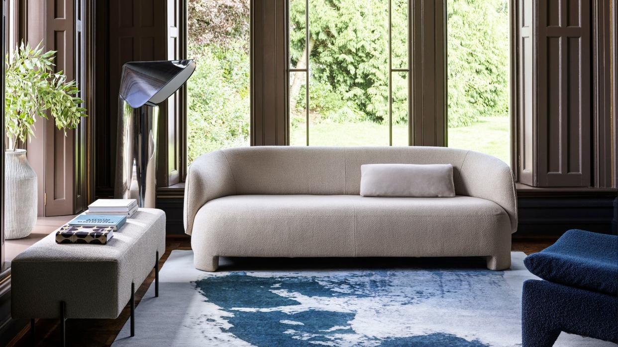  Living room with large windows, a white boucle sofa and an ink blue marbling effect rug. 