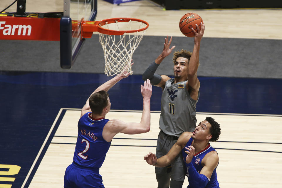 West Virginia forward Emmitt Matthews Jr. (11) shoots while defended by Kansas guard Christian Braun (2) and forward Jalen Wilson (10) during the first half of an NCAA college basketball game Saturday, Feb. 6, 2021, in Morgantown, W.Va. (AP Photo/Kathleen Batten)