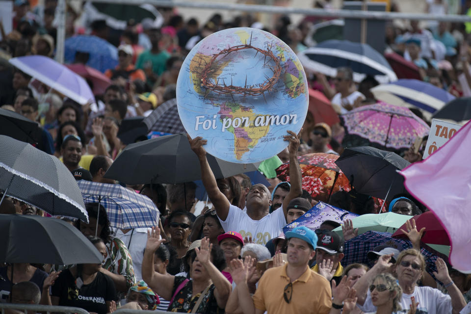 A man holds up a banner depicting a globe with a crown of thorns and a message that reads in Portuguese: "It was for love" during an International Grace of God church event led by televangelist R.R. Soares, with President Jair Bolsonaro in attendance, at Botafogo beach in Rio de Janeiro, Brazil, Saturday, Feb. 15, 2020. Tens of thousands of people gathered to celebrated the 40th anniversary of the evangelical church. (AP Photo/Leo Correa)