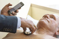 In this Monday, July 8, 2019 photo, James Thomas, a cardiologist at Northwestern Hospital in Chicago examines Dennis Calling, a retired Chicago inspector using Eko Duo, a new device for cardiovascular screening. Northwestern is involved in a study testing the new artificial intelligence technology which combines a stethoscope with an electrocardiogram. To improve detection of heart murmurs the system uses an algorithm based on recordings of thousands of heartbeats. (AP Photo/Amr Alfiky)