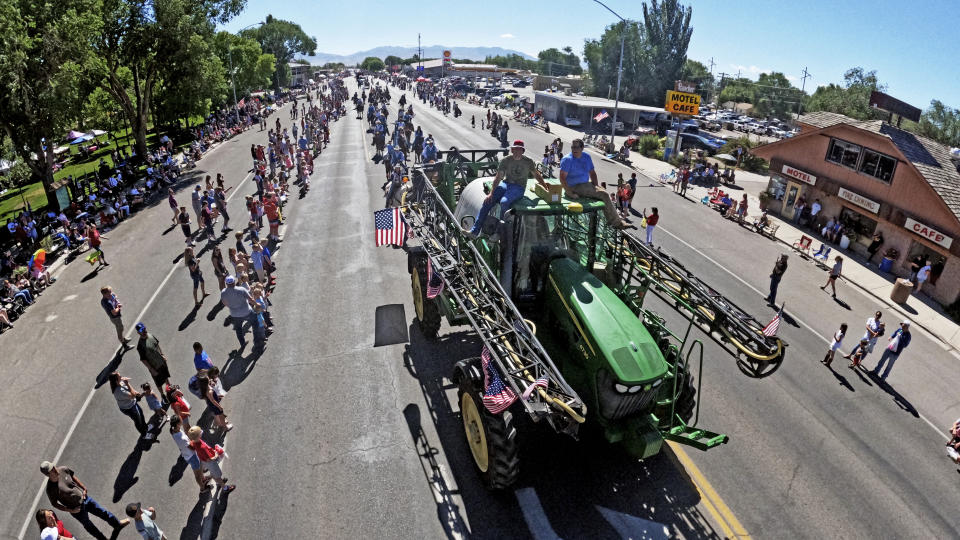 A tractor drives along Main Street during the Fourth of July parade Monday, July 4, 2022, in Delta, Utah. In this tiny Utah town surrounded by cattle, alfalfa fields and scrub-lined desert highways, hundreds of workers over the next few years will be laid off as the coal power plant closes— casualties of environmental regulations and competition from cheaper energy sources. (AP Photo/Rick Bowmer)