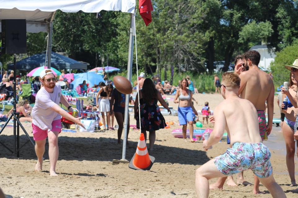 Partygoers toss a football on Ferry Beach during Aquapalooza in Charlevoix on Saturday, July 16.