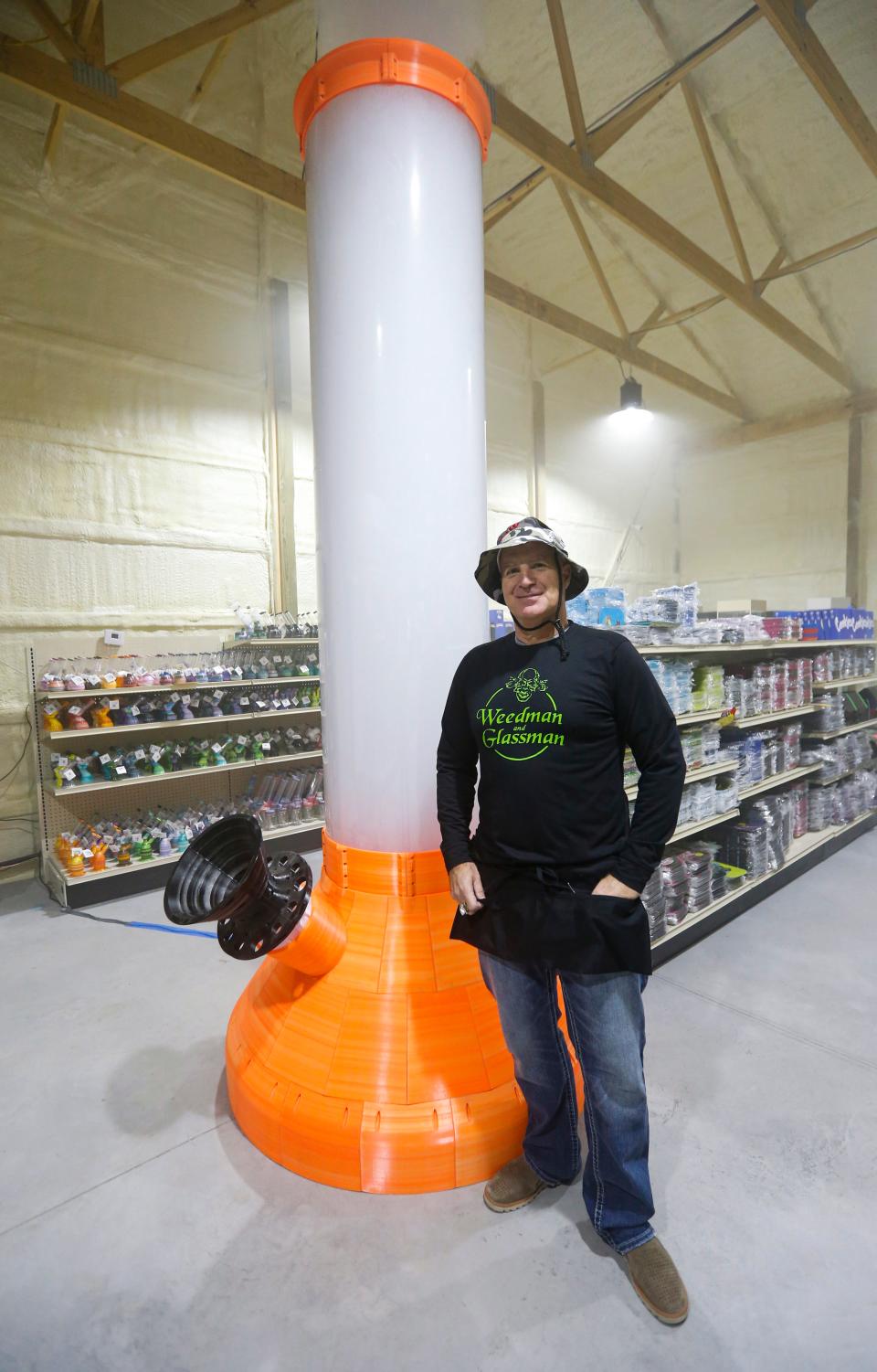 Joesph Spina stands next to the 11-foot tall, 150-pound bong on display at his business Weedman and Glassman in Bolivar on Friday Feb. 3, 2023. 