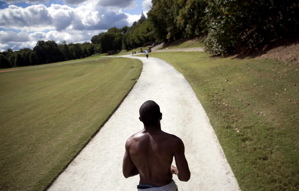 FILE- In this Oct. 14, 2013 file photo, a jogger runs around a trail in Piedmont Park in Atlanta. Like New York’s Central Park, the nearly 200-acre green space in Midtown gives Atlanta residents and visitors a tranquil setting to picnic, play games, walk their dogs and relax in the meadow or along the shores of Lake Clara Meer. The park also plays host to major city events. The annual 10-kilometer Fourth of July Peachtree Road Race ends there and the Dogwood Festival and Music Midtown festival are held there. (AP Photo/David Goldman, File)