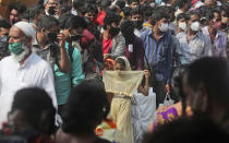 FILE- In this April 14, 2021 file photo, people wearing masks as a precaution against the coronavirus stand in queues to board trains as they try to leave Mumbai, the capital of the worst affected Maharashtra state in India. India's health system is collapsing under the worst surge in coronavirus infections that it has seen so far. Medical oxygen is scarce. Intensive care units are full. Nearly all ventilators are in use, and the dead are piling up at crematoriums and graveyards. Such tragedies are familiar from surges in other parts of the world — but were largely unknown in India. (AP Photo/Rafiq Maqbool, File)