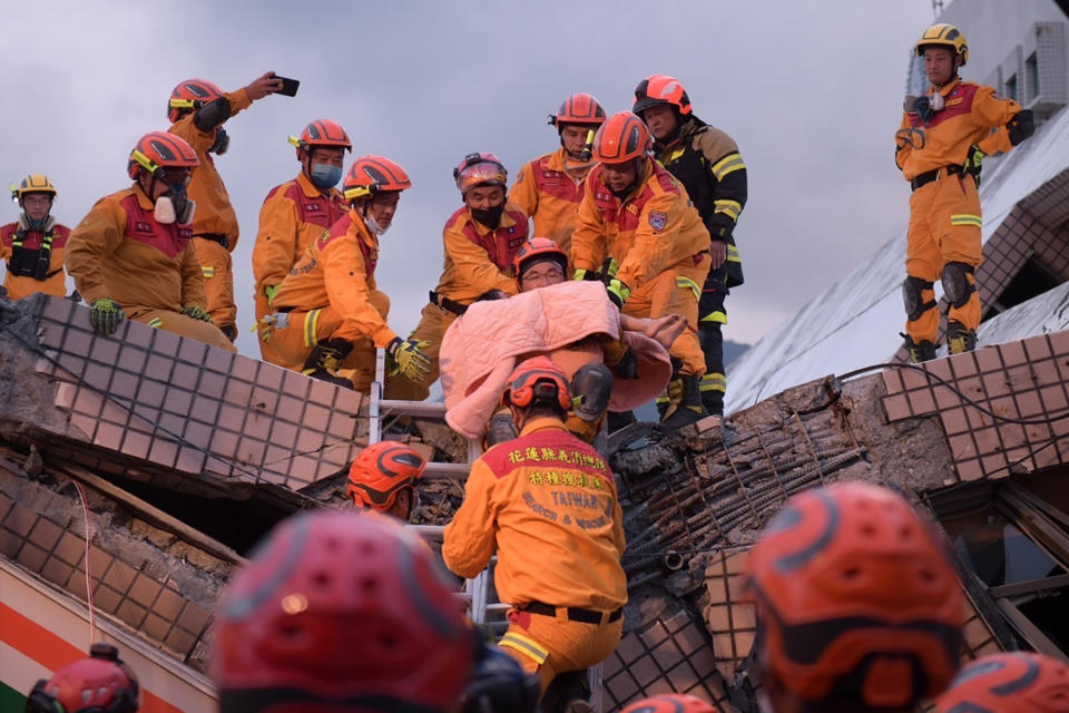 In this photo provided by Hualien City Government, a victim, one's legs partly seen at center, is carried by firefighter during a rescue operation following an earthquake in Yuli township, Hualien County, eastern Taiwan, Sunday, Sept. 18, 2022. A strong earthquake shook much of Taiwan on Sunday, toppling at least one building and trapping two people inside and knocking part of a passenger train off its tracks at a station.(Hualien City Government via AP)