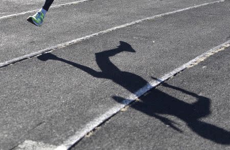 A sportsman casts a shadow on a race track while training at a local stadium in the southern city of Stavropol, Russia, November 10, 2015. REUTERS/Eduard Korniyenko/Files