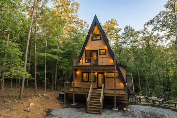 A long gravel drive leads to the multi-story home, which sits surrounded by soaring trees.