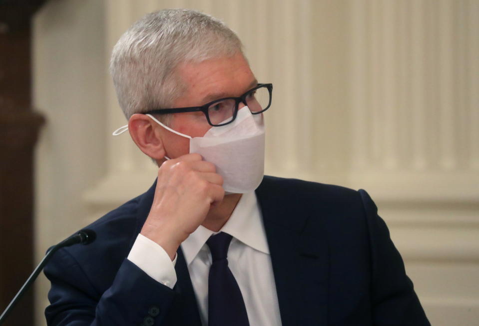 Apple Inc CEO Tim Cook leans on his hand while listening to President Biden 