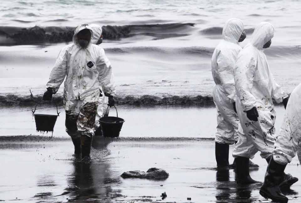 Workers use buckets to remove crude oil during a clean up operation on the beach of Prao Bay on Samet Island in Rayong province eastern Thailand Tuesday, July 30, 2013. About 50,000 liters (13,200 gallons) of crude oil that leaked from a pipeline operated by PTT Global Chemical Plc, has reached the popular tourist island in Thailand's eastern sea despite continuous attempts to clean it up.  (AP Photo)