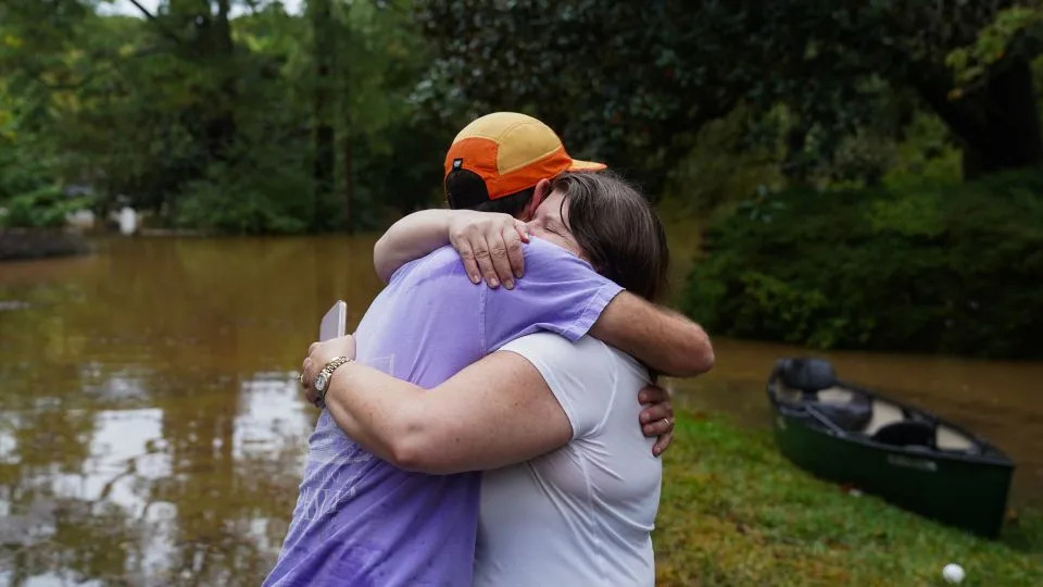 Dan Murphy hugs his colleague after bringing his canoe to rescue them from their flooded home as the streets are flooded near Peachtree Creek on September 27, 2024 in Atlanta, Georgia. - Megan Varner/Getty Images