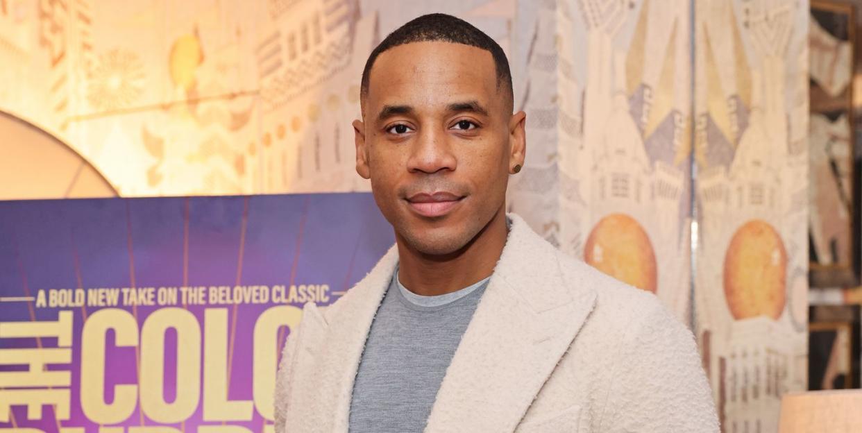 reggie yates at the color purple screening, wearing a grey jumper and a cream coat