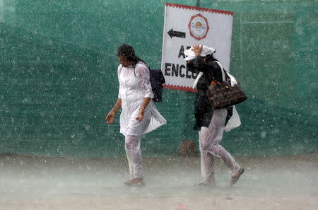 Women arrive during a hailstorm at the venue of World Culture Festival on the banks of a river in New Delhi, India, March 11, 2016. REUTERS/Adnan Abidi