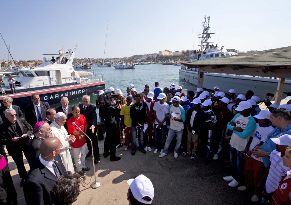 Pope Francis, left, speaks to migrants, wearing white caps, during his visit to the island of Lampedusa, southern Italy, Monday July 8, 2013. Ten years after Pope Francis made a landmark visit to the Italian island of Lampedusa to show solidarity with migrants, he is joining Catholic bishops from around the Mediterranean this weekend in France to make the call more united, precisely at the moment that European leaders are again scrambling to stem the tide of would-be refugees setting off from Africa. (AP Photo/Alessandra Tarantino, File)