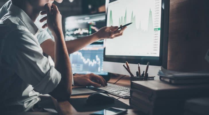 Person on the phone points at charts on a computer screen.