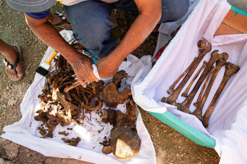 José Alfredo Yam Vargas cleans the bones and skull of his brother-in-law, who died in February 2019, at the cemetery of Pomuch on Oct. 22, 2022.