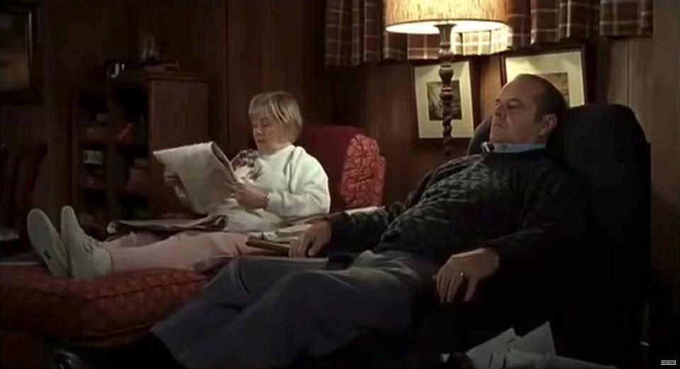 June Squibb and Jack Nicholson play a married couple in About Schmidt. They sit in patterned armchairs next to each other, while June's character reads a newspaper on the left.