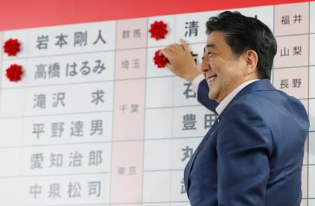 Japan's Prime Minister Shinzo Abe, who is also leader of the ruling Liberal Democratic Party (LDP), puts a rosette on the name of a candidate who is expected to win the upper house election, at the LDP headquarters in Tokyo