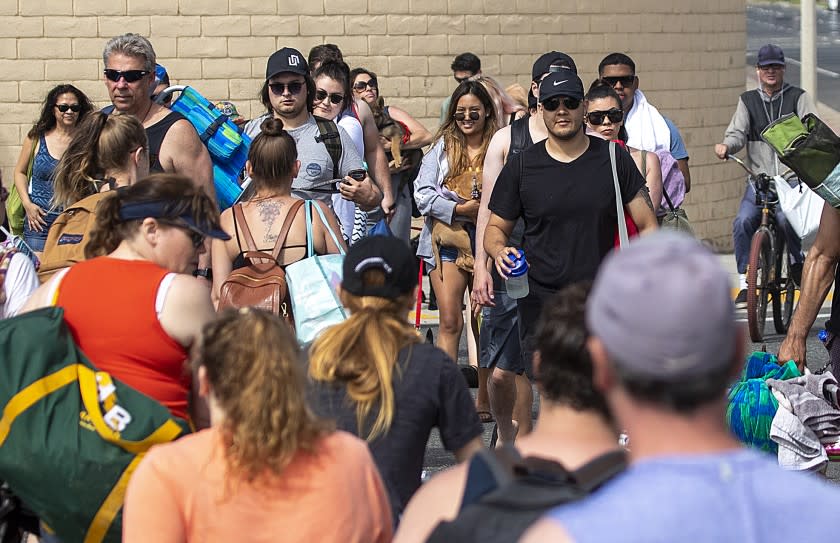 HUNTINGTON BEACH, CA -- SATURDAY, APRIL 25, 2020: With beach parking lots closed down, crowds of people cross Pacific Coast Highway to and from the beach as they join thousands of beach-goers enjoy a warm, sunny day at the beach amid state-mandated stay-at-home and social distancing mandate to stave off the coronavirus pandemic in Huntington Beach, CA, on April 25, 2020. (Allen J. Schaben / Los Angeles Times)