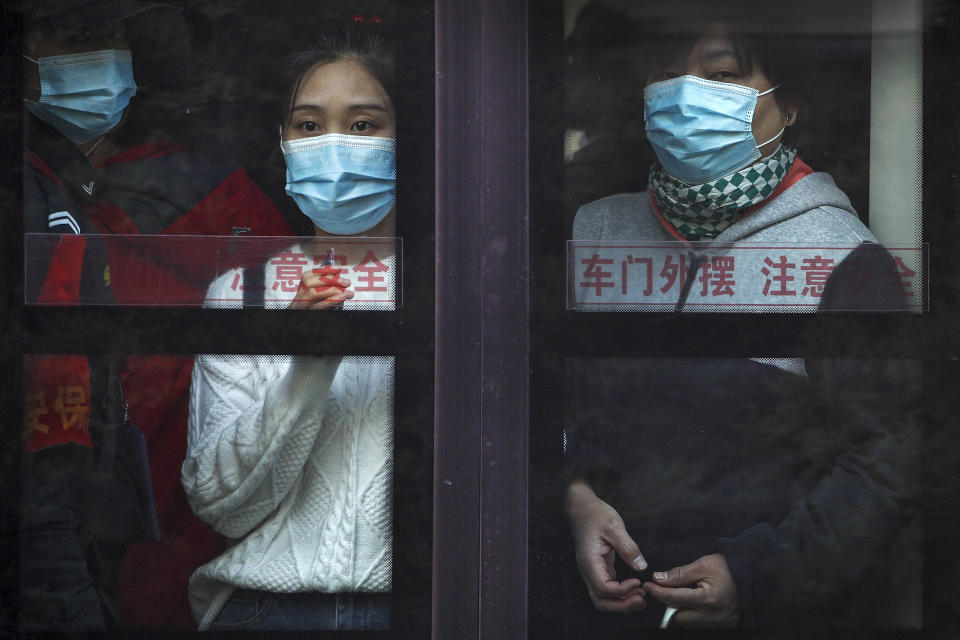 Commuters wearing face masks to help curb the spread of the coronavirus look out from a traveling bus during the morning rush hour in Beijing, Monday, Oct. 26, 2020. Schools and kindergartens have been suspended and communities are on lockdown in Kashgar, a city in China's northwest Xinjiang region, after more than 130 asymptomatic cases of the coronavirus were discovered. (AP Photo/Andy Wong)