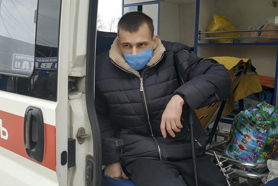 A separatist, wearing face mask to protect against coronavirus, sits in an ambulance after he was exchanged near the checkpoint Horlivka, eastern Ukraine, Thursday, April 16, 2020. Ukrainian forces and Russia-backed rebels in eastern Ukraine have begun exchanging prisoners in a move aimed at ending their five-year long war. (AP Photo/Alexei Alexandrov)