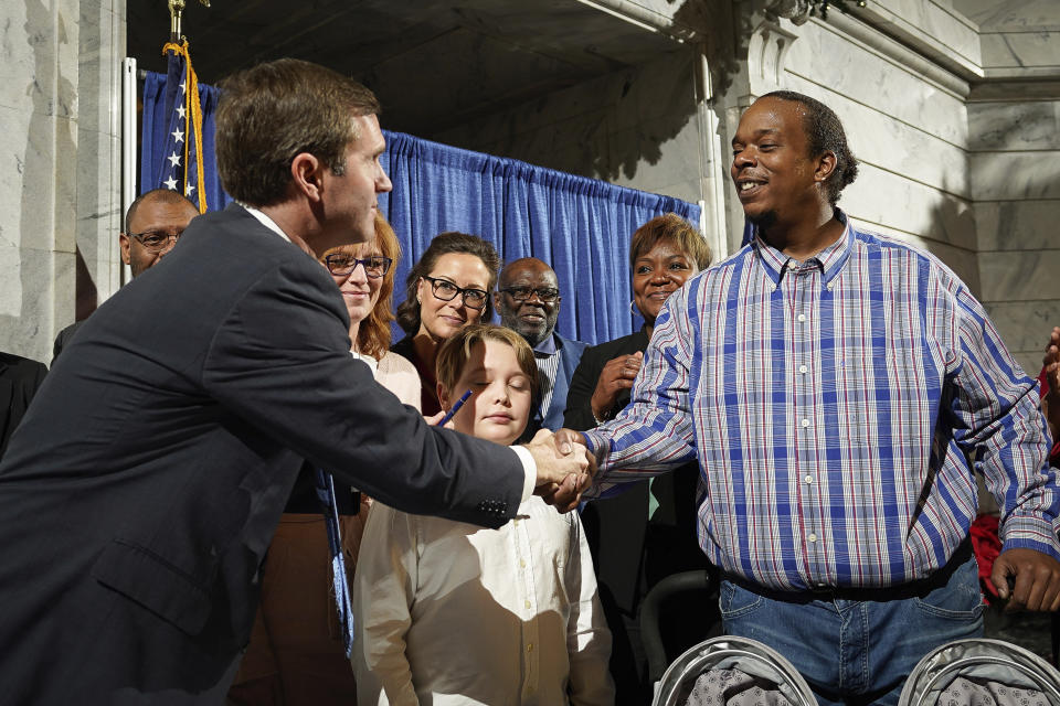 Rynn Young, of Louisville, Kentucky, shakes the hand of Kentucky Democratic Governor Andy Beshear after the signing of an executive order to reinstate the voting rights of over 100,000 non-violent felons who have completed their sentences, at the Capitol in Frankfort, Ky., Thursday, Dec. 12, 2019. Young was convicted of a drug possession when he was 18 and will have his voting rights restored with today's order. (AP Photo/Bryan Woolston)