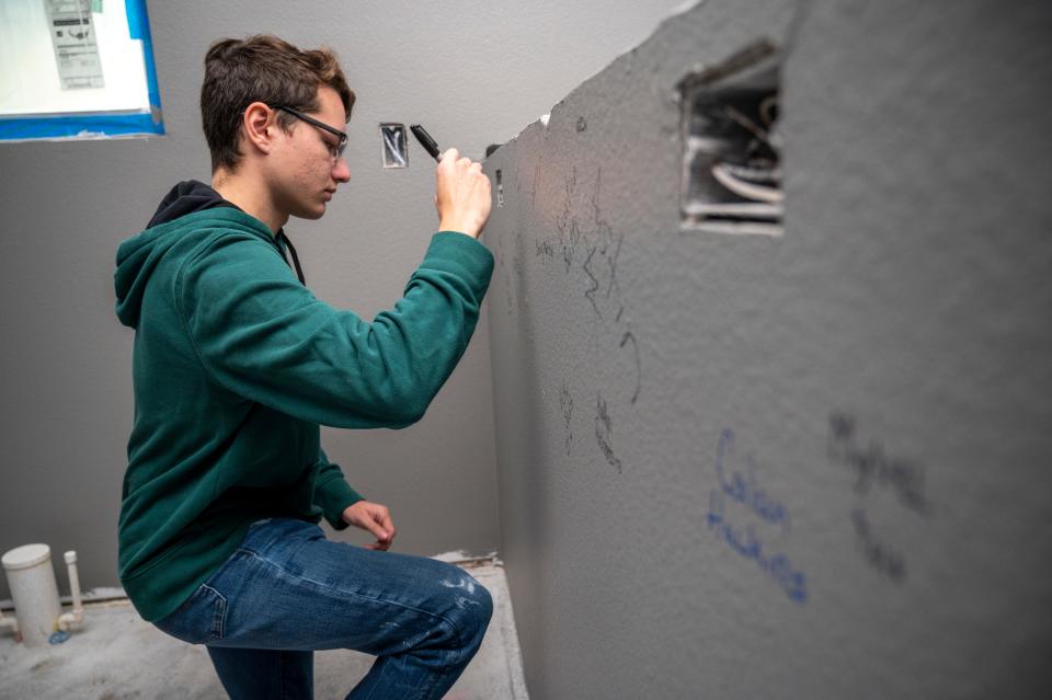 A student from the Leesburg High School Construction Academy signs a wall of the house he helped build with Habitat for Humanity of Lake and Sumter in January.