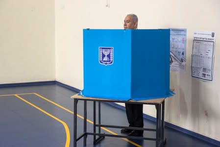 Israeli Prime Minister Benjamin stands behind a voting booth as he votes during Israel's parliamentary election at a polling station in Jerusalem