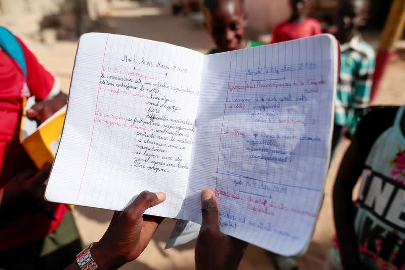 A child shows his notes from a lesson about coronavirus symptoms and prevention in Pikine, on the outskirt of Dakar
