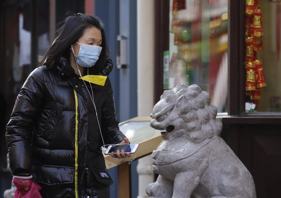 A woman wears a mask as she walks through China Town in London, Friday, Feb. 7, 2020. The director-general of the World Health Organization says a drop in the number of new coronavirus cases for two days is “good news” but cautions against reading too much into that. China reported 31,161 cases in mainland China in its update Friday. (AP Photo/Kirsty Wigglesworth)