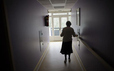 A woman suffering from Alzheimer's disease, walks in a corridor in a retirement house in Angervilliers, eastern France - Credit: SEBASTIEN BOZON/AFP