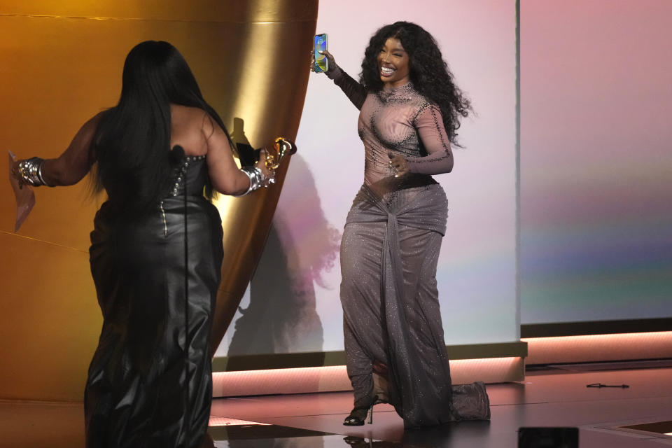 Lizzo, left, presents the award for best R&B song to SZA for "Snooze" during the 66th annual Grammy Awards on Sunday, Feb. 4, 2024, in Los Angeles. (AP Photo/Chris Pizzello)