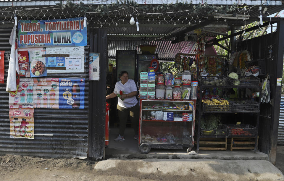 Maritza Pacheco trabaja en la pequeña tienda que abrió hace cuatro meses, afuera de su casa en el barrio Primero de Diciembre en Soyapango, El Salvador, el jueves 2 de marzo de 2023. (AP Foto/Salvador Meléndez)